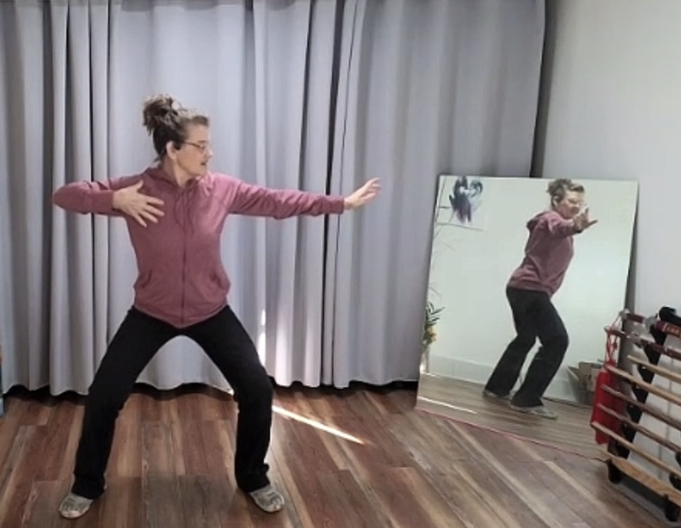 female fitness instructor teaching Qigong doing archer pose