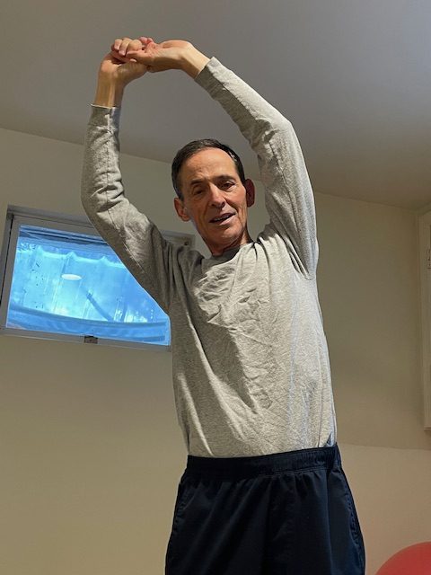 Man stretching arms over his head.